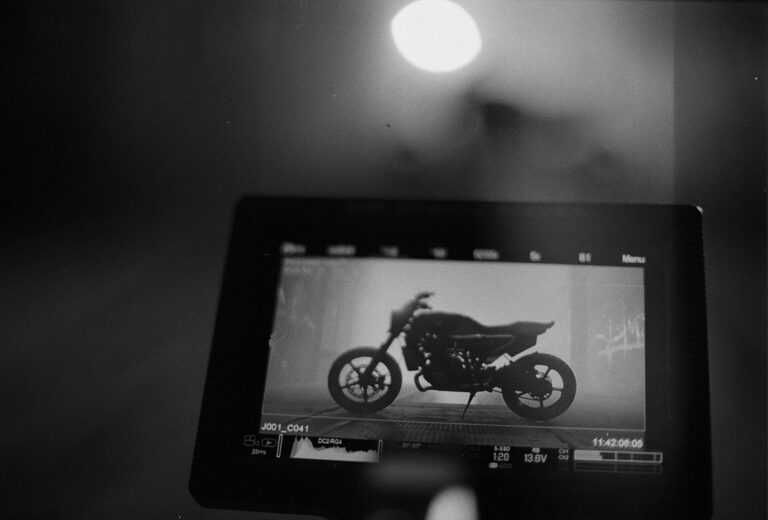 Schwarzweißfoto: Auf dem Kameramonitor ist die Silhouette eines Motorrads in einer nebligen Halle zu sehen.