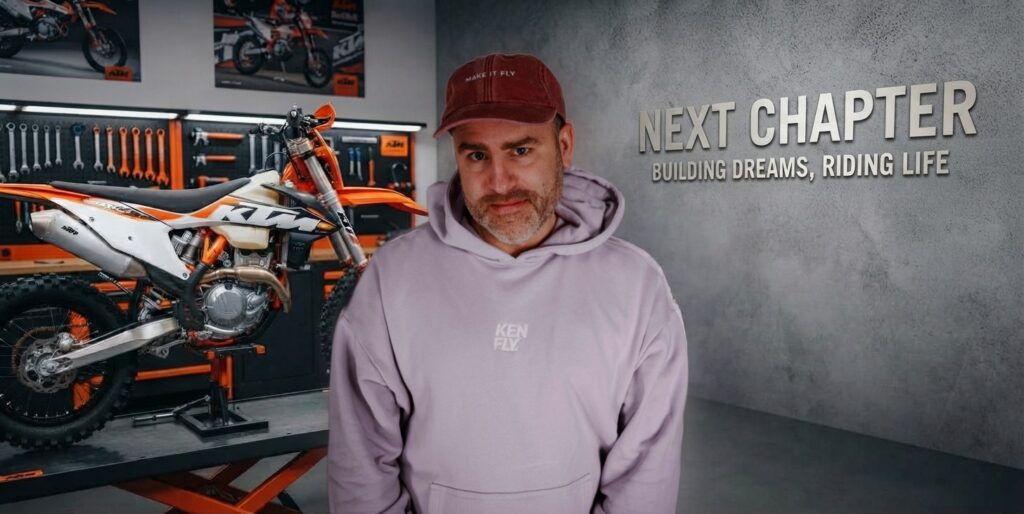 Oli in Kappe und Hoodie in einer Garage neben einer KTM Enduro, an der Betonwand der Schriftzug Next Chapter, Building Dreams, Riding Life